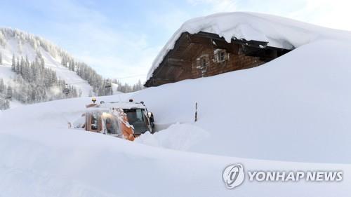 오스트리아 잘츠부르크 인근 마을에 내린 눈이 집 지붕까지 쌓인 가운데 제설차가 11일(현지시간) 집 앞으로 길을 내고 있다./ 사진=연합뉴스