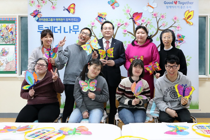 손태승 우리금융그룹 회장(뒷줄 왼쪽 세번째)이 16일 경기도 안산시 사회복지법인 명휘원을 방문해 지적장애인들과 함께 만든 미술작품 앞에서 기념사진을 촬영하고 있다.[사진 제공: 우...