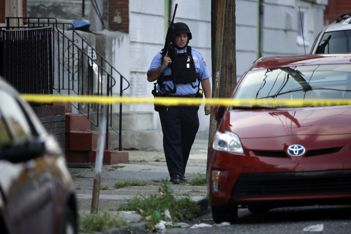 A police officer patrols the block near a house as they investigate an active shooting situation, We...