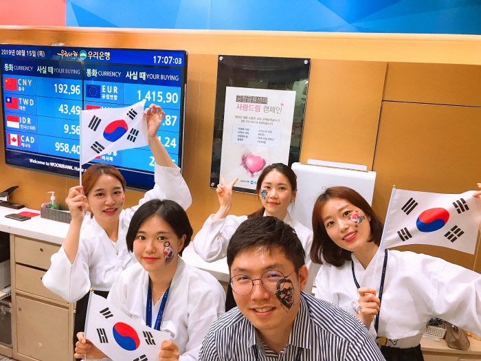 독립투사 복장과 김구 선생 등으로 페이스 페인팅을 한 우리은행 공항영업본부 직원들이 15일 인천공항 환전소에서 광복 74주년 기념 이벤트를 펼치며 태극기를 흔들고 있다. [사진제공...